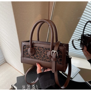 Detailed macro view of the leopard print patch and silver metal buckle on the brown handbag