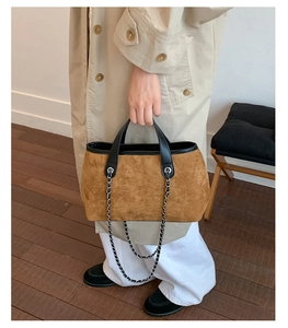 Detailed macro view of the premium brown suede texture and elegant silver chain on the handbag