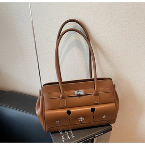 Detailed view of brown leather shoulder bag featuring three functional front pockets and locks