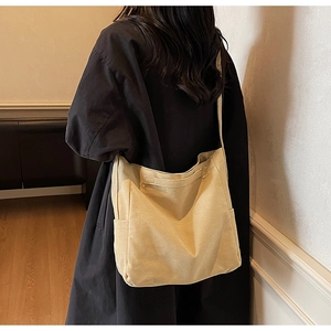 Dettaglio di una grande borsa a tracolla in tela beige con tasca laterale e trama robusta