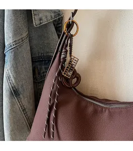 Detail of dark brown pebble leather hobo bag with vintage abacus and fringe charms