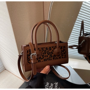 Detail of leopard print crossbody bag featuring brown leather trim and silver metal hardware