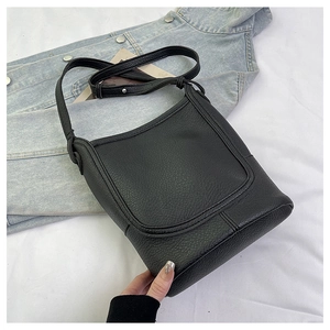 Detail of black pebbled leather bucket bag with silver hardware and adjustable strap