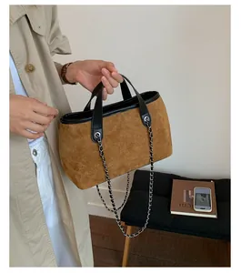 Brown suede tote bag with black leather trim and silver chain strap shown in use