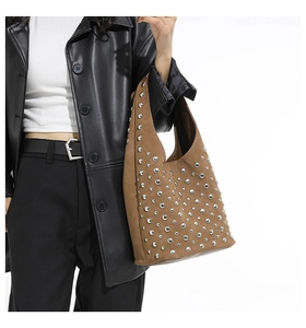 Dettaglio di una borsa Hobo marrone scamosciata con borchie argentate indossata da modella