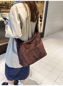 Vue latérale du grand sac cabas en daim marron porté par un mannequin en ville