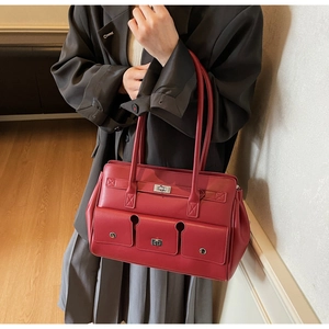 Deep red leather tote bag showing three front pockets with silver twist locks on model