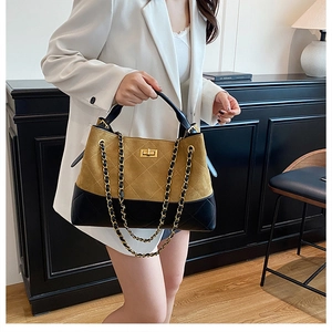 Detail of two-tone quilted bucket bag with gold twist lock and metal chain strap