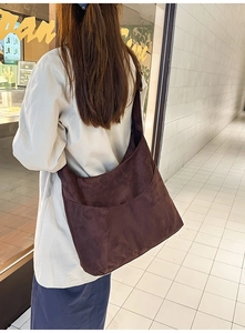 Mannequin de dos avec un grand sac hobo en daim marron café dans un couloir intérieur