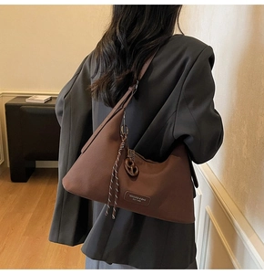 Detail of the textured brown hobo bag with vintage leather tag and braided strap detail