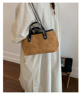 Macro shot of brown suede tote bag with chain strap and black leather handles