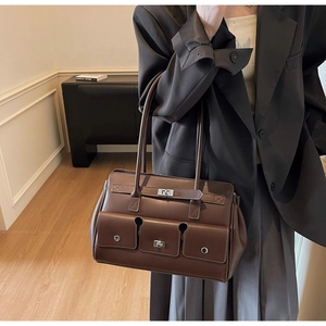 Detail of vintage brown leather handbag featuring metal lock and three front utility pockets