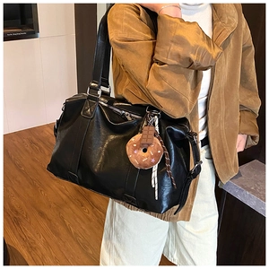 Close-up of black glossy large tote bag with plush charm on a female model
