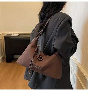 Detail of the brown matte leather Hobo bag with brand logo and braided tassel