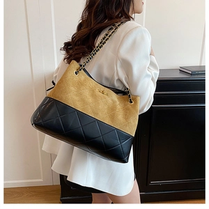 Model view of a large two-tone quilted tote bag with gold chain and turn-lock closure