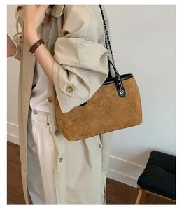 Detail of vintage brown suede tote bag with silver chain strap and black leather trim