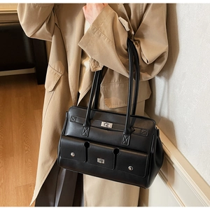 Close-up of black leather shoulder bag with silver twist lock and rivet details