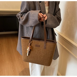 Brown vintage suede tote bag with fringe charm shown on a model in professional attire