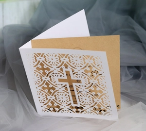 Macro shot of laser-cut cross and floral details on white and kraft invitation card