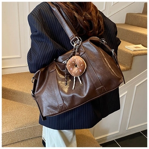 Brown tote bag with donut plushie worn by model on stairs, highlighting size and style