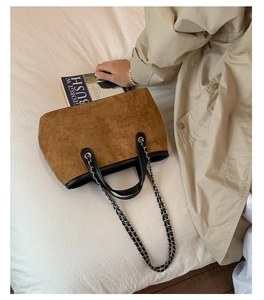 Detail of vintage brown suede tote bag with black leather straps and silver metal chain