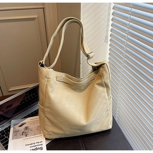 Dettaglio della borsa a tracolla in tela beige con tasca laterale e cinghia