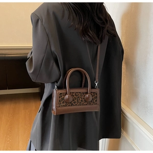Detail of vintage leopard print crossbody bag with leather trim worn by a model