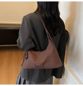 Detail showing coffee brown leather hobo bag with adjustable strap and side woven lanyard