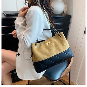 Detail of a color-block bucket bag with mustard suede and black quilted leather with chain strap