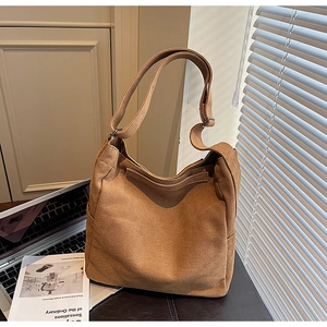 Dettaglio della tracolla larga regolabile su una borsa hobo in tela marrone da donna
