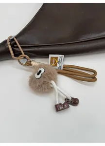 Détail d'un joli charme de sac en peluche marron avec de grands yeux sur un sac à main