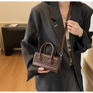 Detail of a brown leopard print handbag worn with a chic grey blazer in a lifestyle setting