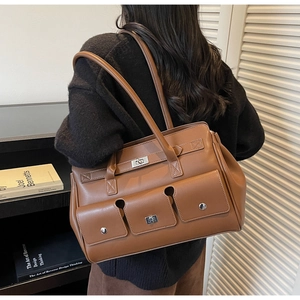 Close-up of caramel brown leather tote bag featuring multiple front pockets and silver twist locks