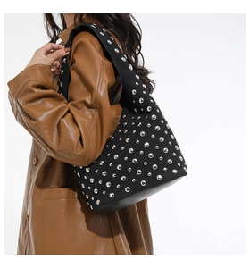 Dettaglio di borchie argentate su una borsa tote nera stile rock con tracolla larga