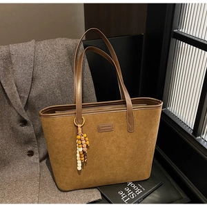 Detail view of large brown suede tote bag with leopard lining and wooden bead pendant