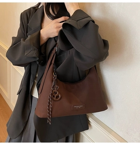 Close-up of a dark brown half-moon crossbody bag with a braided rope knot detail