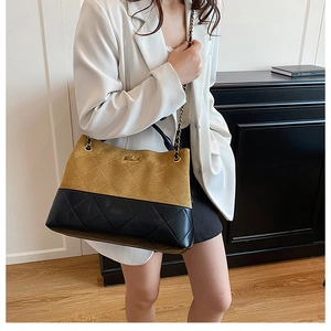 Detailed close-up of brown suede and black quilted leather crossbody bucket bag with chain