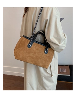 Detail of the suede tote bag showing brown suede texture and black leather trim accents