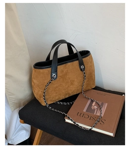 Detail shot of caramel suede bucket bag with black leather handle and silver chain strap