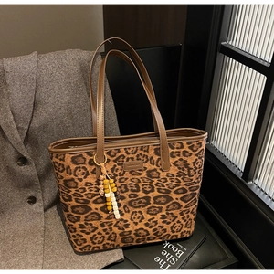 Detail of leopard print tote bag with beaded tassel charm and faux leather branding