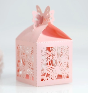 Close-up of pink laser-cut wedding candy box with intricate floral patterns and butterfly top