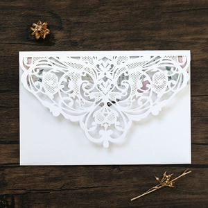 Macro detail of laser-cut white lace envelope with floral wedding invitation card