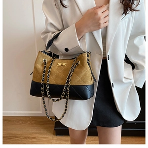 Close-up of a quilted bucket bag with chain strap and gold twist lock in yellow and black