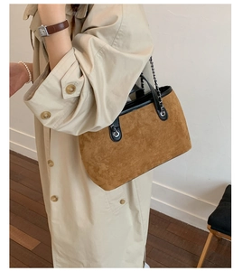 Detail of caramel suede bucket bag with black leather trim and chain strap