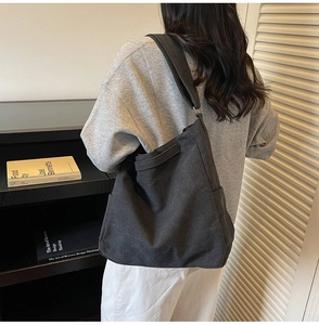 Dettaglio di una borsa hobo in tela nera che mostra la tasca laterale e il tessuto
