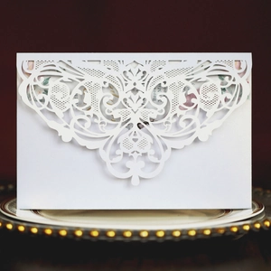 Macro detail of laser-cut lace wedding invitation with floral patterns on red background