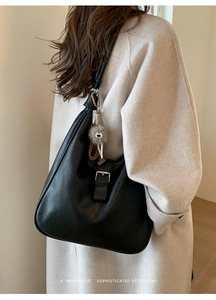 Détail d'un grand sac cabas en cuir noir mat avec boucle argentée et breloque en peluche