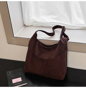 Détail de la texture en daim marron foncé et de la large bandoulière de ce grand sac