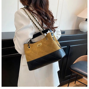 Detail of quilted two-tone suede tote bag featuring a gold twist-lock and chain strap