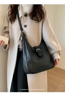 Détail du sac hobo rétro noir avec boucle argentée et charm en peluche sur modèle